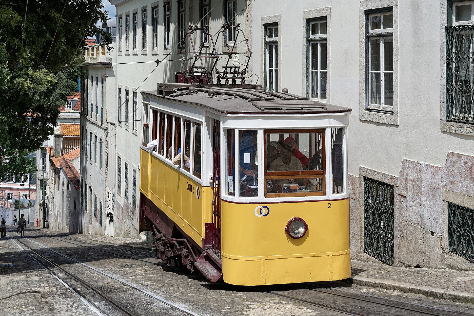 A yellow Elevador da Glória funicular car on a Lisbon street