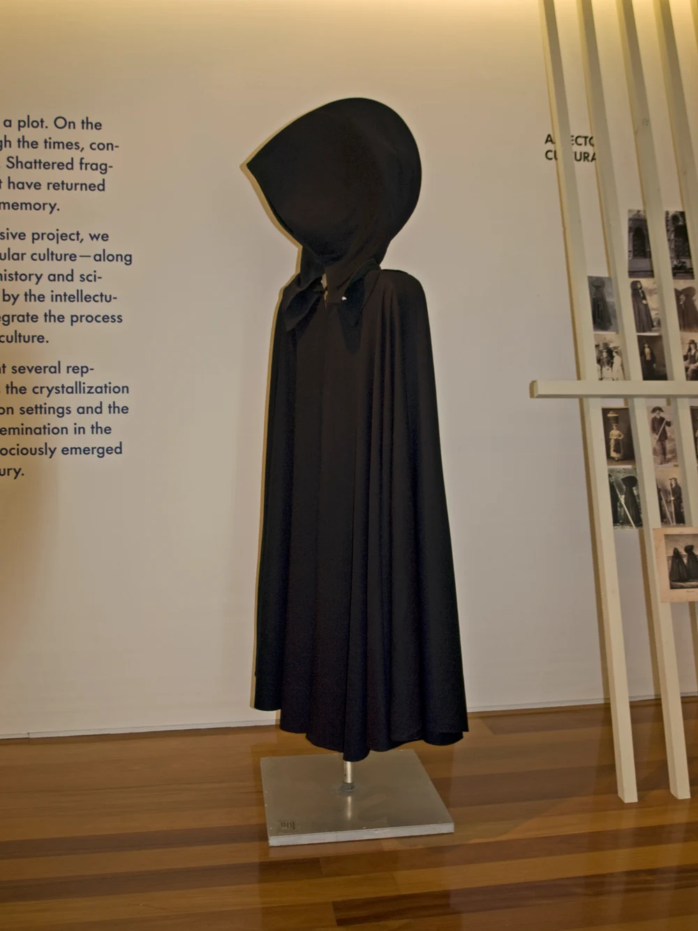 A dark Azorean cape with a large projecting hood displayed on a mannequin.