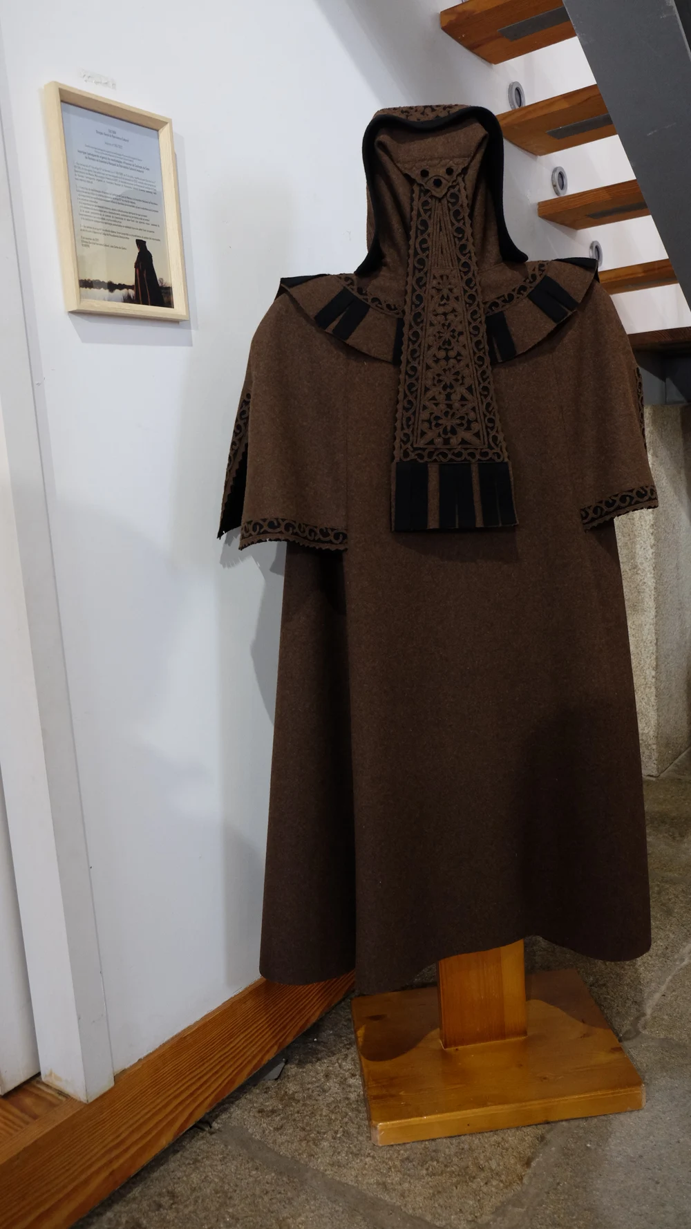 A brown Capa de Honras with cut decoration, a short shoulder cape and a hanging hood panel.
