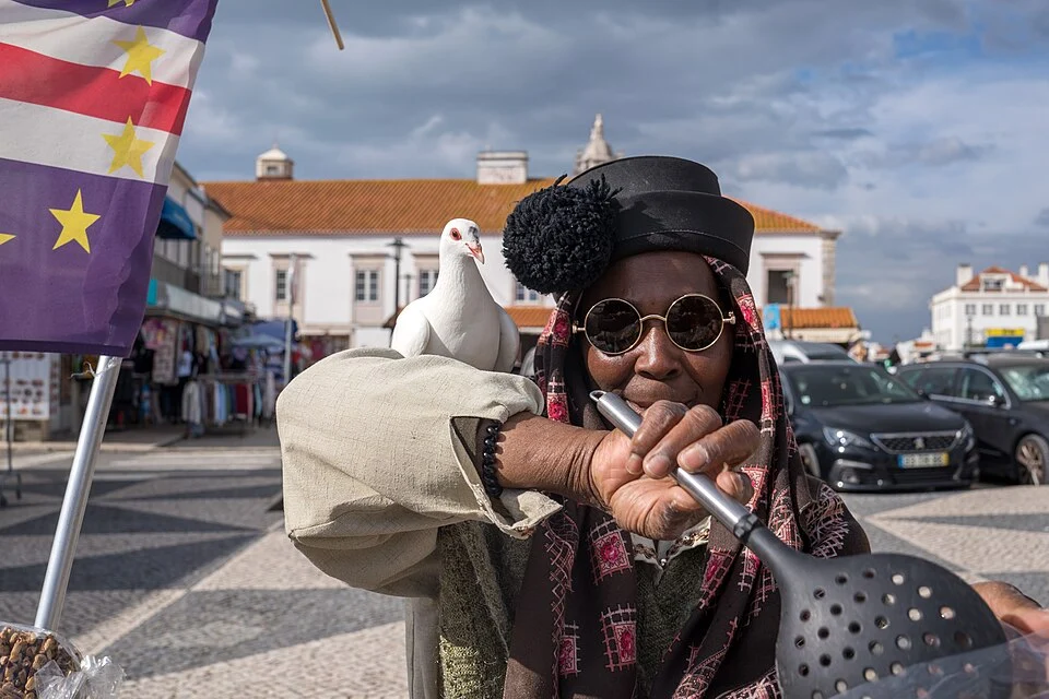 A seller in Nazaré wears a dark tasseled hat over a patterned headscarf.